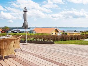 a wooden deck with an umbrella and a house at 6 person holiday home in R nde in Rønde
