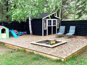 un patio trasero con un arenero y 2 sillas y una casa de juegos en 12 person holiday home in V ggerl se en Bøtø By