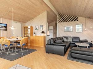 a living room with a black leather couch and a table at 10 person holiday home in Løkken-By Traum in Løkken