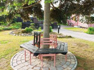 deux chaises assises sur un banc autour d'un arbre dans l'établissement 6 person holiday home in Kors r, à Korsør
