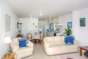 ein Wohnzimmer mit 2 weißen Sofas und einer Küche in der Unterkunft Self Contained Cottage Pukekohe in Auckland