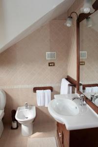 łazienka z umywalką, toaletą i lustrem w obiekcie B&B Domus Gratiae w mieście Ostia