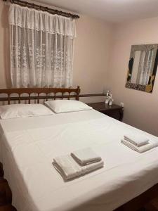 a bedroom with a white bed with towels on it at Your Holiday House in Porto Rafti