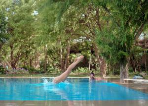 a woman in a swimming pool with her leg in the air at PushkarOrganic - Lux farm resort with pool in Pushkar