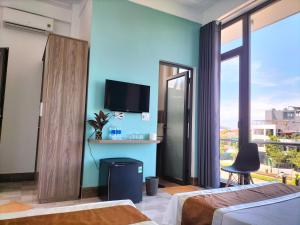 a bedroom with a blue wall with a tv and a window at HOA MAI Plus Hostel in Dong Hoi