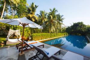 a pool with chairs and an umbrella next to a resort at Tamarind Hill Galle in Galle