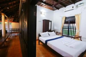 a bedroom with a bed and a large window at Palmy Lake Resort in Alleppey