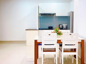 - une cuisine avec une table en bois et des chaises blanches dans l'établissement Cookies Homestay Vung Tau Melody (Căn Hộ Biển), à Vung Tau