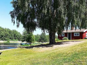 een boom in het gras naast een rood huis bij Holiday home NORRTÄLJE IX in Norrtälje