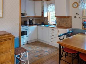 諾爾泰利耶的住宿－Holiday home NORRTÄLJE IX，厨房配有白色橱柜和木桌
