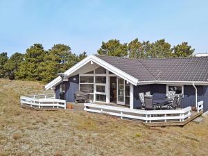 una pequeña casa azul con porche y sillas en Holiday home Fanø CCVI en Fanø