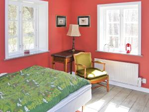 a bedroom with a bed and a chair and windows at Holiday home VANKIVA in Vankiva