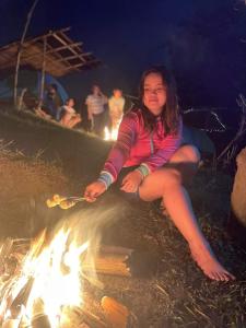 a woman sitting next to a camp fire at Raw Camping at Camping Paradise Singalong Mountain Garden in Antipolo