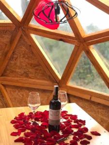a bottle of wine and two glasses on a table with roses at “Entres sueños”, el lugar ideal para soñar in La Calera