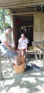 two people sitting on a chair in a shack at Raw Camping at Camping Paradise Singalong Mountain Garden in Antipolo