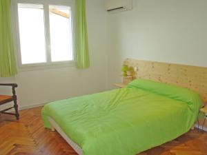 a bedroom with a green bed and a window at Les Gîtes Malidri in Pontonx-sur-lʼAdour