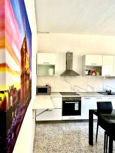 een keuken met witte kasten en een schilderij aan de muur bij Camag Apartment - Very close to Airport in Birżebbuġa