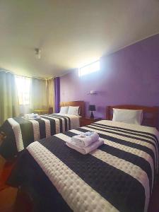 1 dormitorio con 3 camas y toallas. en Samay Wasi - Aeropuerto, en Lima
