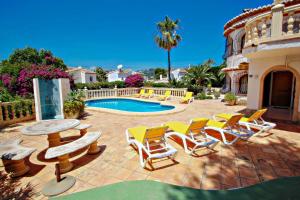 モライラにあるRondel - sea view villa with private pool in Costa Blancaのパティオ(椅子、テーブル、プール付)