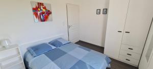 Schlafzimmer mit einem blauen Bett und weißen Schränken in der Unterkunft Appartement devant la plage avec piscine in Concarneau