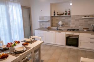 una cocina con armarios blancos y una mesa con frutas. en Le Dimore di Corte Madama, en Casarano