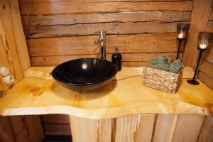 ein Badezimmer mit einem schwarzen Waschbecken auf einer Holztheke in der Unterkunft Gaismas klēts in Upmaļciems