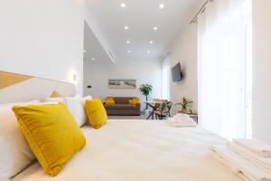 a white bedroom with a large bed with yellow pillows at Baia Flegrea Meublè in Bacoli