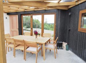 una mesa de madera con sillas y un jarrón de flores en Kotare BandB en Geraldine