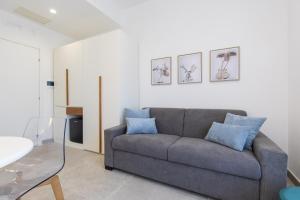 a living room with a gray couch with blue pillows at Baia Flegrea Meublè in Bacoli