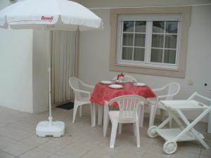 a table and chairs with a table and an umbrella at Apartamento na Cidade do Surf in Peniche