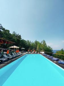 uma grande piscina com cadeiras e guarda-sóis em Rocas Roja Beach Hotel Faralya em Faralya