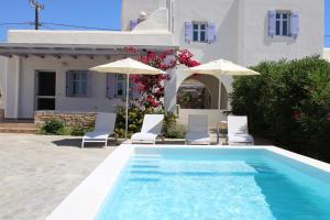 a swimming pool with chairs and umbrellas next to a house at Blue Xenia - Villa 3 in Chrissi Akti