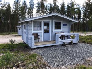 un pequeño cobertizo blanco con porche y 2 sillas en Koli caravan cottages en Kolinkylä