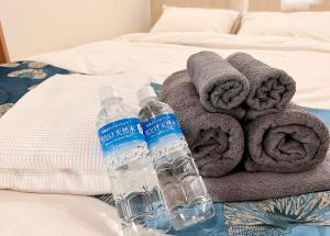 two bottles of water sitting on a bed with towels at Hotel mond omiya in Saitama