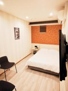 a bedroom with a bed and a tv and a chair at Hotel mond omiya in Saitama