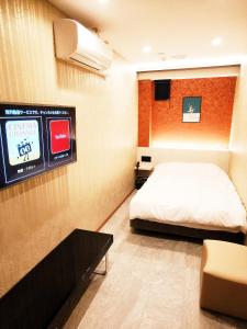 Hotel mond omiya في سايتاما: غرفة نوم مع سرير وتلفزيون على الحائط