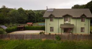 uma casa verde com uma cerca em frente em Agropensiunea Cetatuia em Luncaviţa