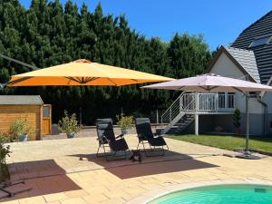 twee stoelen en twee parasols naast een zwembad bij Belle chambre spacieuse et au calme in Schweighouse-sur-Moder