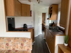 a kitchen with wooden cabinets and a couch in a room at Cornish coastal retreats- 74 newquay view in Porth
