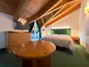 a bedroom with a bed and a wooden table at B&B Garni Villa Campitello in Campitello di Fassa