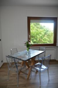 a glass table with two chairs and a vase with flowers at Due camere e una bici in Venasca
