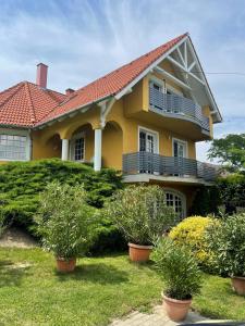 a yellow house with a balcony and bushes at Vár-Lak Resort in Balatonederics