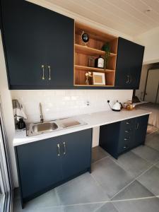 a kitchen with dark blue cabinets and a sink at 10 Jock Meiring Guesthouse unit 1 in Bloemfontein
