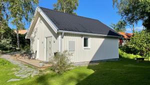 een witte schuur met een veranda in een tuin bij Floda, Minihus på 62m2 för plats för 4 vuxna och 2 barn in Floda