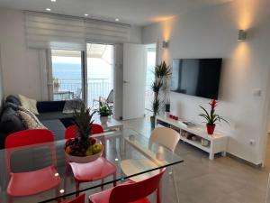 ロザスにあるOverTheSea - PUEBLECITO Apartmentのリビングルーム(ガラステーブル、赤い椅子付)