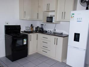 kuchnia z białymi szafkami, czarną kuchenką i lodówką w obiekcie Three Angelz Lodge w mieście Queenstown