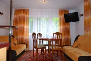 uma sala de estar com uma mesa e cadeiras e um sofá em Leśny Zakątek em Krasnobród