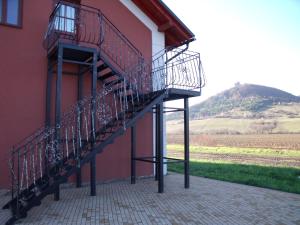 a staircase on the side of a red building with a hill at Penzion Farmer Kapušany in Kapušany