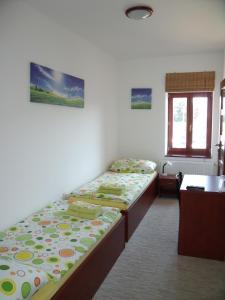 a room with two beds and a desk and a window at Penzion Farmer Kapušany in Kapušany