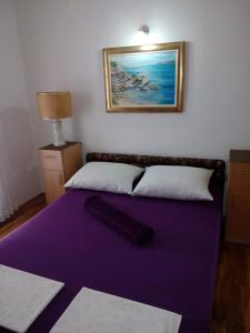 a purple bed with a pillow on top of it at Apartman JURE in Supetar